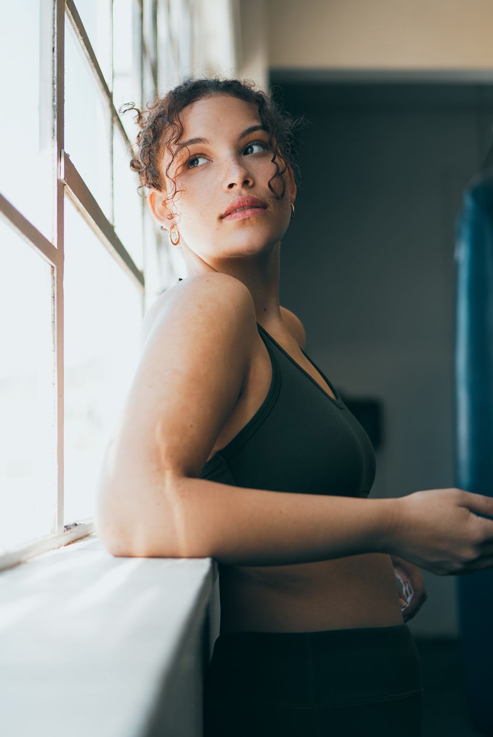 Alpharetta Women's Wellness model in activewear leaning against a window.