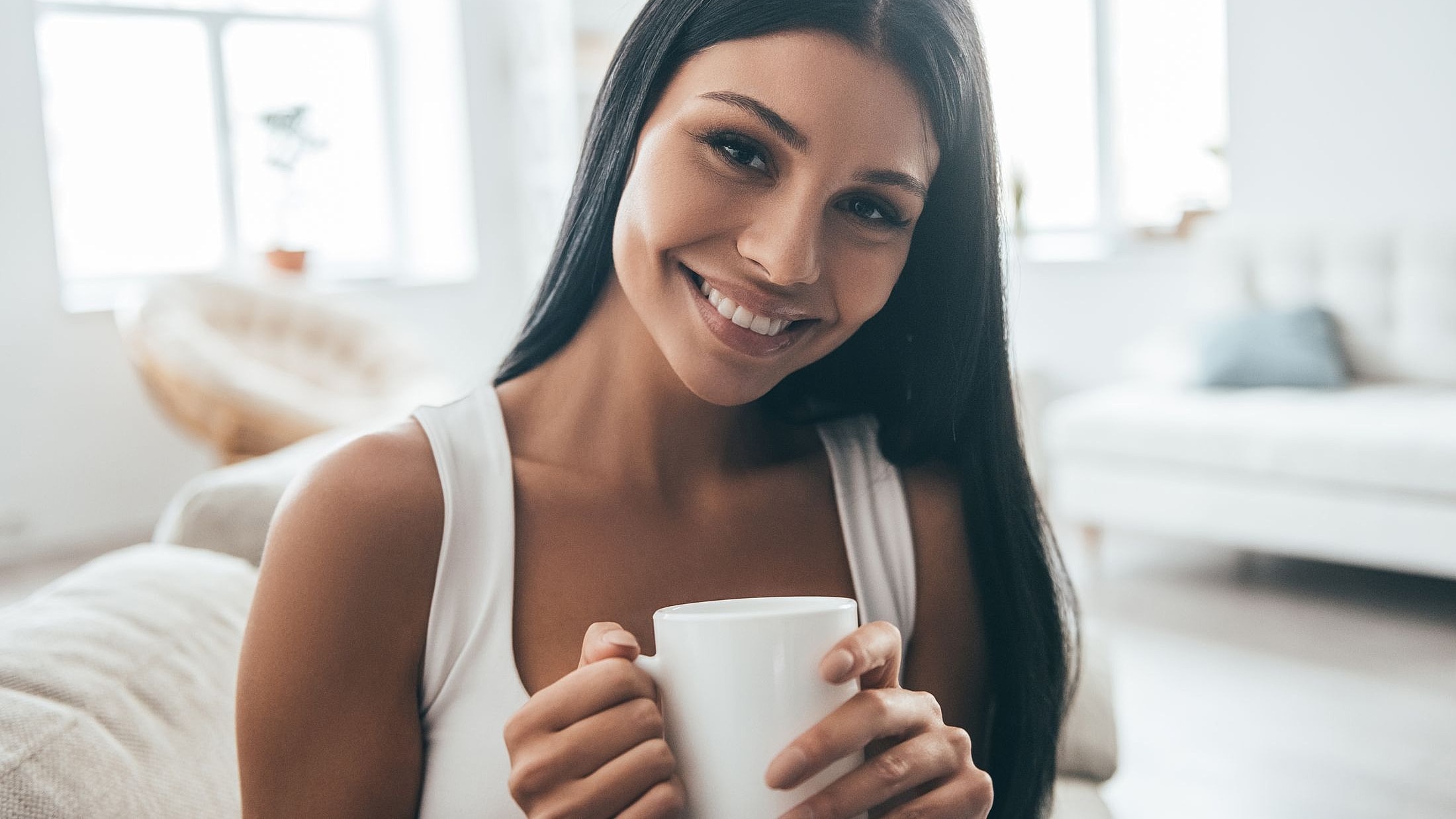 Alpharetta Women's Wellness model holding a cup in bright room.